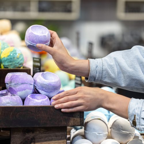 Female hands hold bright bath bombs in a cosmetics store. Body care concept.